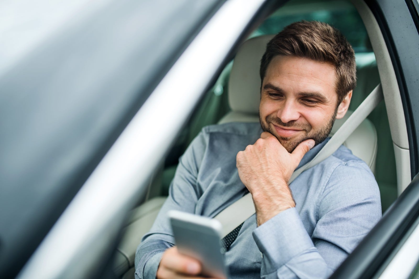 Man checkin in on his phone waiting in his car for his appointment