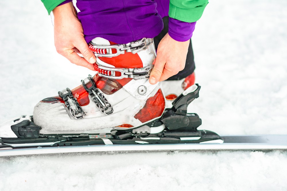 Person tightening ski boots to prevent foot and ankle sports injuries on the ski slopes