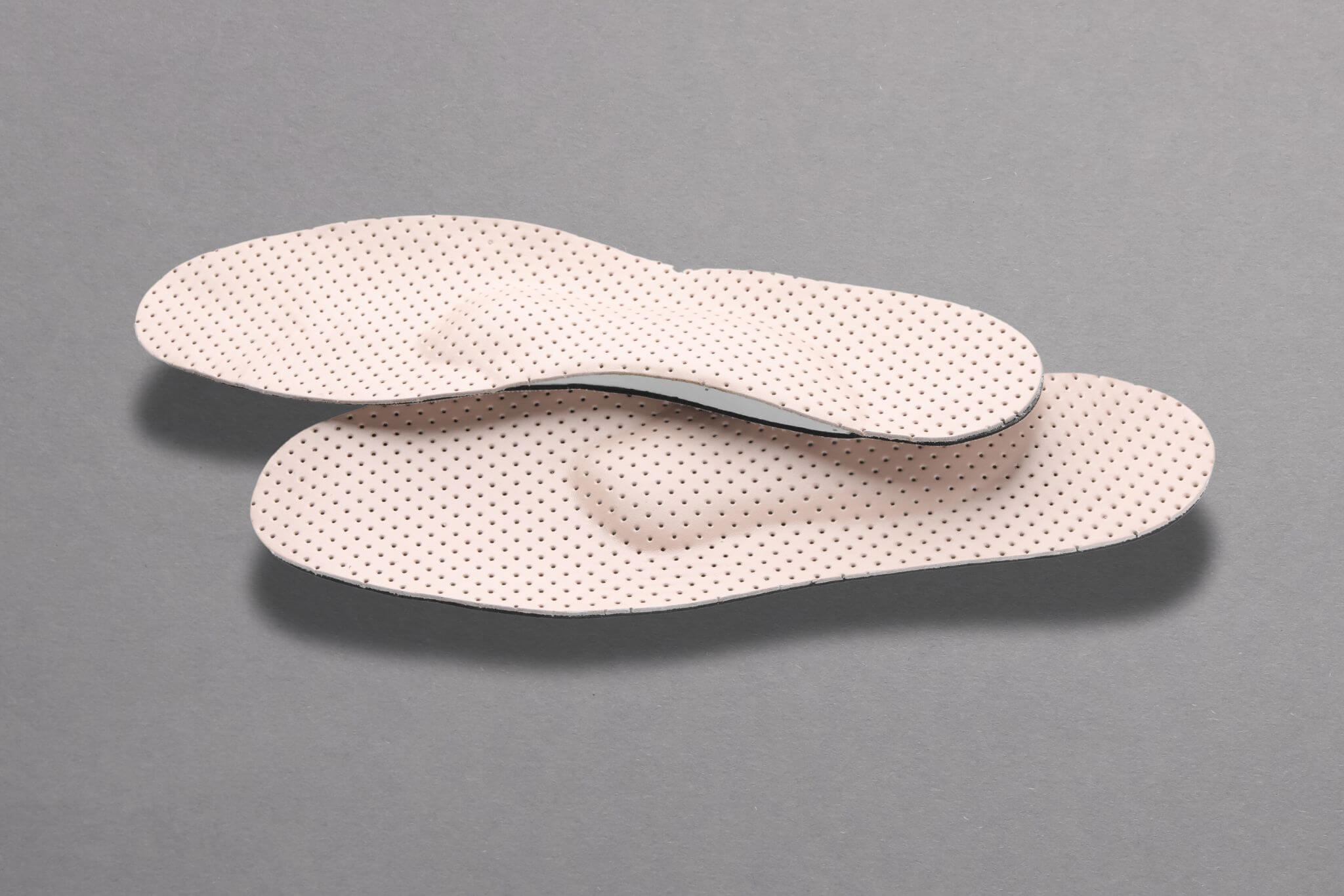 Beige comfortable orthopedic insoles isolated on grey background